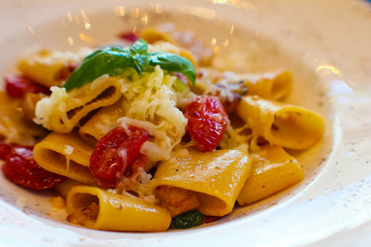 detail of plate with handmade paccheri pasta and saut&eacute;ed aubergines, citrus-flavored confit cherry tomatoes and spotted red in fine Italian restaurant