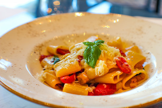 plate with handmade paccheri pasta and saut&eacute;ed aubergines, citrus-flavored confit cherry tomatoes and spotted red in fine Italian restaurant