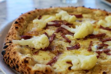 detail of pizza with fresh cauliflower, provola, strips of smoked ham and pepper