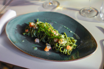 plate of tagliolini with basil and prawns and a glass of wine. Fine serving in a luxury Italian restaurant