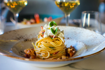 haute cuisine dish with spaghetti with lobster, buffalo stracciatella and a fine white wine. In a luxurious Italian restaurant - 309278538