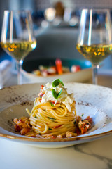 haute cuisine dish with spaghetti with lobster, buffalo stracciatella and a fine white wine. In a luxurious Italian restaurant - 309278542