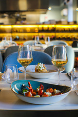 table for two In a luxurious Italian restaurant. Haute cuisine dishes: lobster pieces, cherry tomatoes, buffalo mozzarella and spaghetti with lobster, buffalo stracciatella and two glasses of fine whi - 309278567