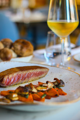 creative italian haute cuisine, tuna belly cooked in its own oil and accompanied by candied pumpkin and sautéed mushrooms and a glass of white wine in fine italian restaurant - 309278773