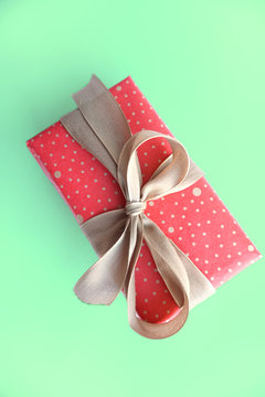 Red Present Gift Box With Gold Bow Isolated On Green Background.