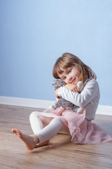 Naklejka premium Girl hugs a fluffy cat toy staying on the floor.