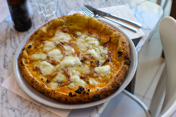 pizzeria table with craft beer with empty label and pumpkin cream pizza, bacon, grated provola and grana cheese and a drizzle of extra virgin olive oil.