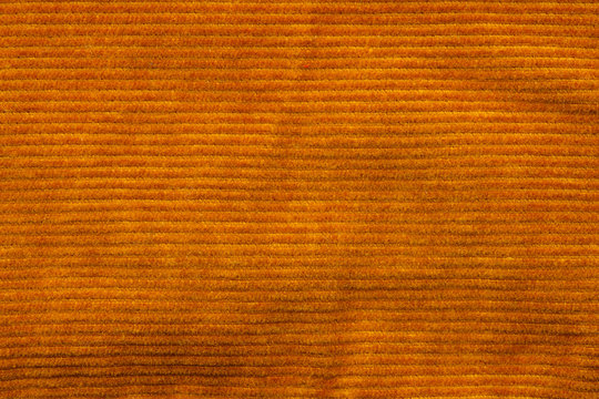 Texture of corduroy velvet fabric close-up. Texture of rufous velvet clothes. Textile fabric as background
