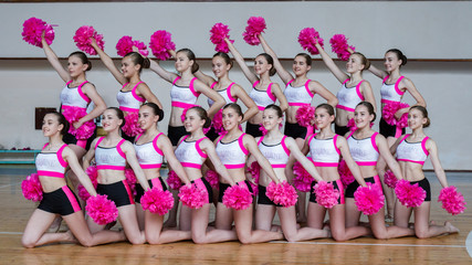 attractive young cheerleaders working out in sports club, group of cheerleaders with pom-poms in...