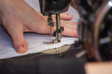 Hands of a woman who sews on an old sewing machine close up