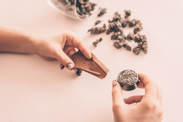 Woman rolling a marijuana joint on white background. Marijuana use concept. Woman preparing and...