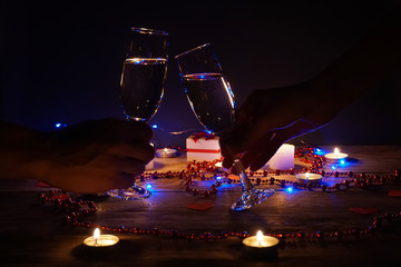 Young couple with glasses of champagne in hands close-up. Romantic candlelit dinner at the table. concept of the celebration, engagement