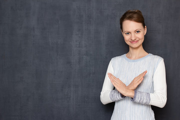 Portrait of happy young woman showing stop or prohibition gesture