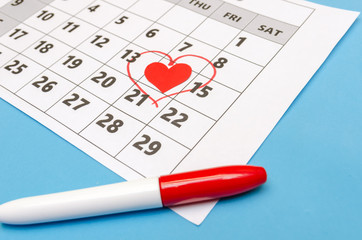 Valentine's day 14 is marked with a heart on the calendar, paper hearts and a felt-tip pen are scattered around. Holiday concept