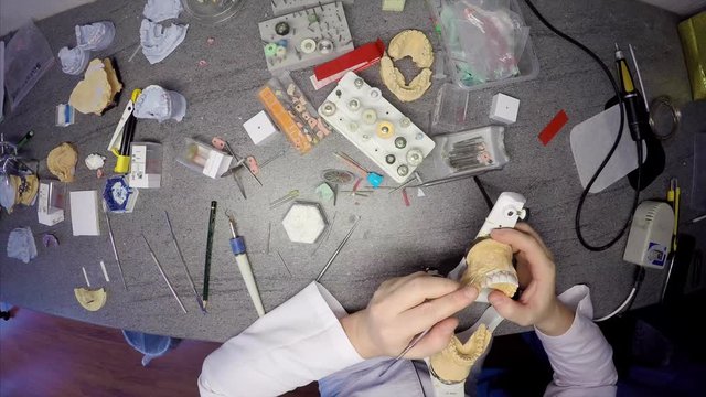 Timelapse from above of dental technician table, he is making a model of jaws and teeth