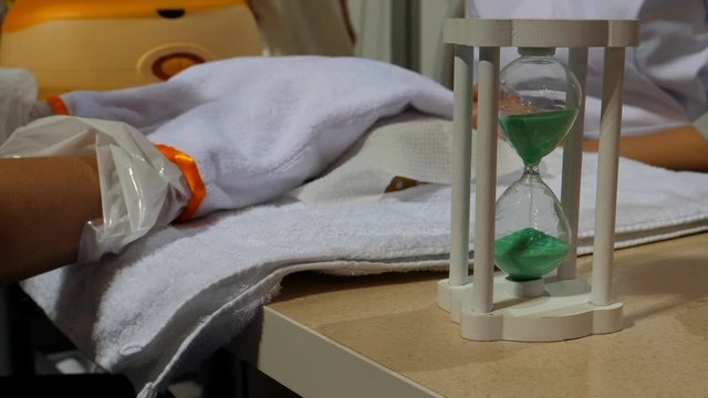 Close up of woman's hands inside of heated mitts having paraffin wax treatment at a beauty salon.