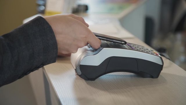Concept of successful payment. Intelligent, professional and qualified young man indoor light room or bright space with soft daylight. Adult male using smartphone to confirm pay the bill