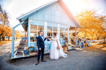 Obraz premium Beautiful romantic wedding couple of newlyweds hugging near blue old house. Autumn