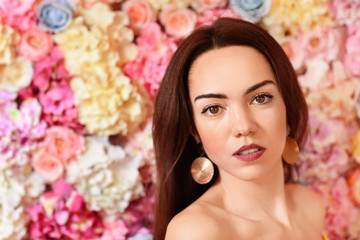 Obraz na płótnie Canvas Portrait of beautiful young woman near wall made of flowers
