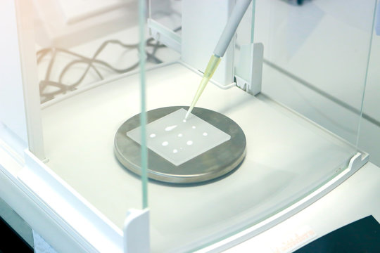 Scientist pipette a sample to sheet PMMA acrylic plate on analytical balance to know the exact weight before measuring the radiation protection of UV sunscreen cosmetic by using ultraviolet meter
