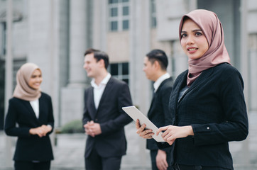 Portrait of cheerful happy businesswoman wearing black suit  standing  and holding tablet