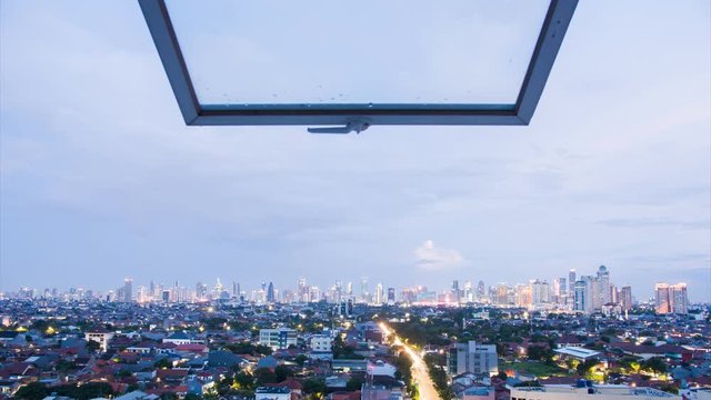 Timelapse of Jakarta city panorama at sunset against the background of a raised window pane. Indonesia.