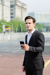 Fototapeta premium Portrait of young businessman Texting to Someone on his Mobile Phone with Happy Facial Expression.
