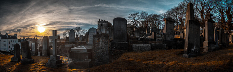 EDINBURGH, SCOTLAND DECEMBER 14, 2018: old, desolated and grungy tombstones, memorials and headstones in the graveyard with the sun rising at New Calton Burial Ground - obrazy, fototapety, plakaty