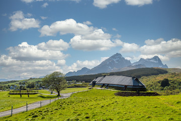Lofotr long house, a home for vikings in the viking era, during daytime with white clouds. Mountains in the background. Architecture, history and viking concept.
