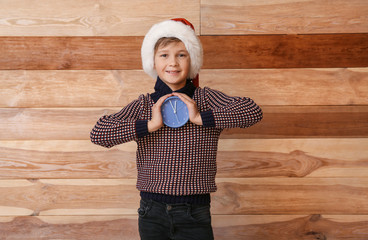 Little boy with alarm clock on wooden background. Christmas countdown concept
