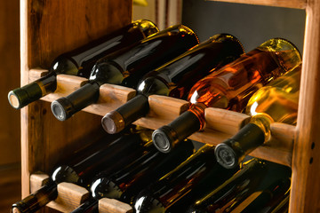 Wooden holder with bottles of wine in cellar - obrazy, fototapety, plakaty