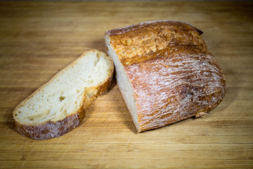 Ciabatta bread on a wooden board with sliced slice. Baked