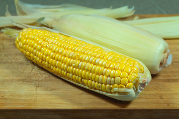 A sheaf of corn in leaves and peeled on a wooden board. Two pieces