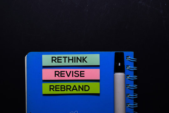 Rethink Revise Rebrand write on Sticky Notes. Top view isolated on black background.
