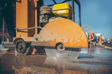 cutting concrete floor with worker cutting concrete road with diamond saw blade machine