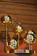 Golden shiny ball candleholder with star holes. Christmas and New Year decoration on the shelf with wooden background. Cozy tealight candle holder