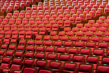 Red PU leather mesh pattern Fabric Cloth with wooden frame on Empty Many chair Seats Row Column in Auditorium Theatre Concert or Seminar grand Conference Hall room with ceiling lighting