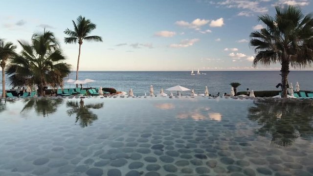 Oceanfront Cabo San Lucas resort with palm trees and scenic view of ocean. Static shot