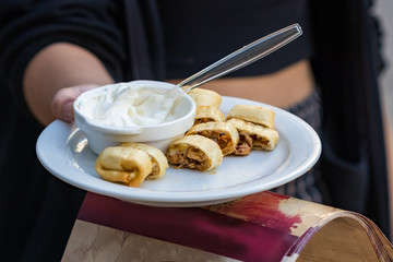 Female hands offering greek chicken wrap to taste on the street, outdoors.