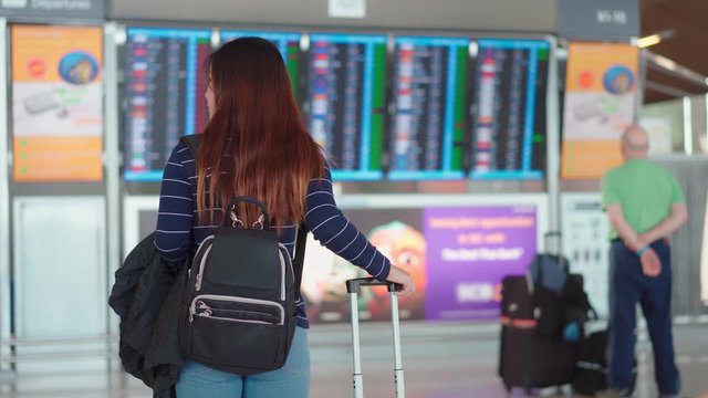 Pretty young woman traveler checking boarding time at airport