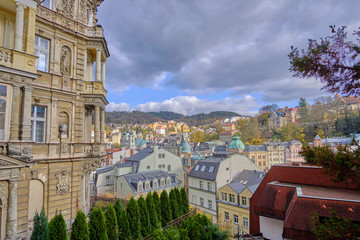 Scenic aerial view of Karlovy Vary - small ancient touristic resort town near the border between Czech Republic and Germany. Beautiful summer cloudy look of little famous town among hills in Czechia