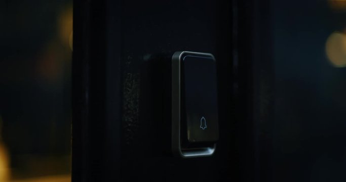 Close up of a male finger is pressing a ring bell in the evening.