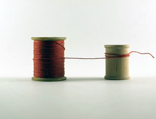 One Vintage Wooden Thread Spool With Red Thread Connected to an Empty Smaller Vintage Wooden Thread...