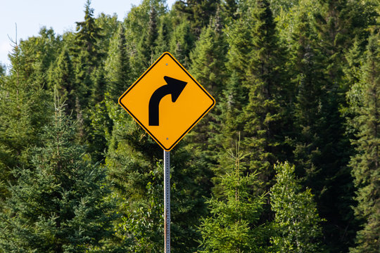 Warning for a curve to the right, Slight bend or curve in the road ahead, Warning road signs, in selective focus view with forest trees background