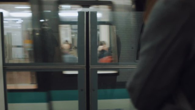 Cinematic close-up camera follows woman waiting for metro train at station platform doors, entering train slow motion.