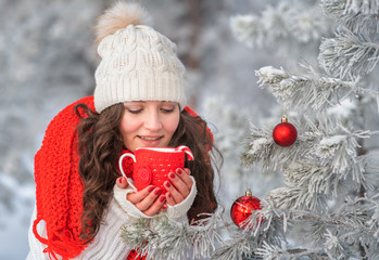girl in winter forest drinking cocoa from a mug
