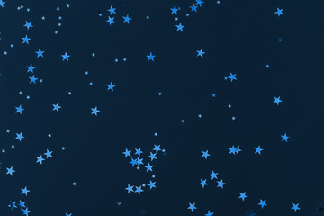 Sparkling stars glitter confetti on blue background. Classic holiday backdrop.