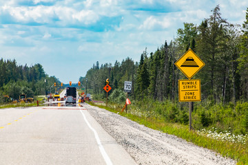 Temporary condition road warning signs on the roadside before road work zone, rumble strips on a bilingual yellow sign, Canadian rural roads