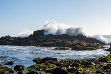 Crashing waves over jagged rocky ocean coastline  .