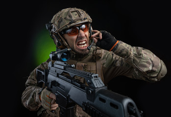 a male soldier in military clothes with a weapon on a dark background